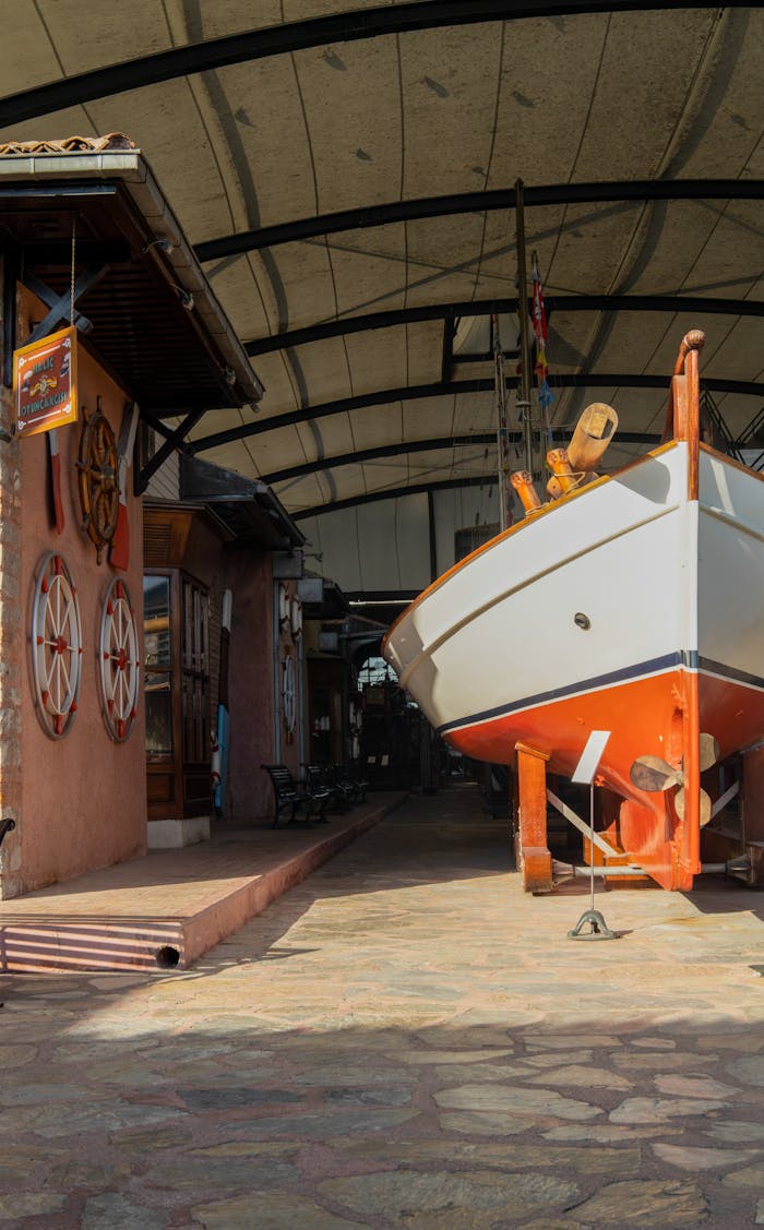 A ship in a covered shipyard adjacent to a decorated building with nautical themes.